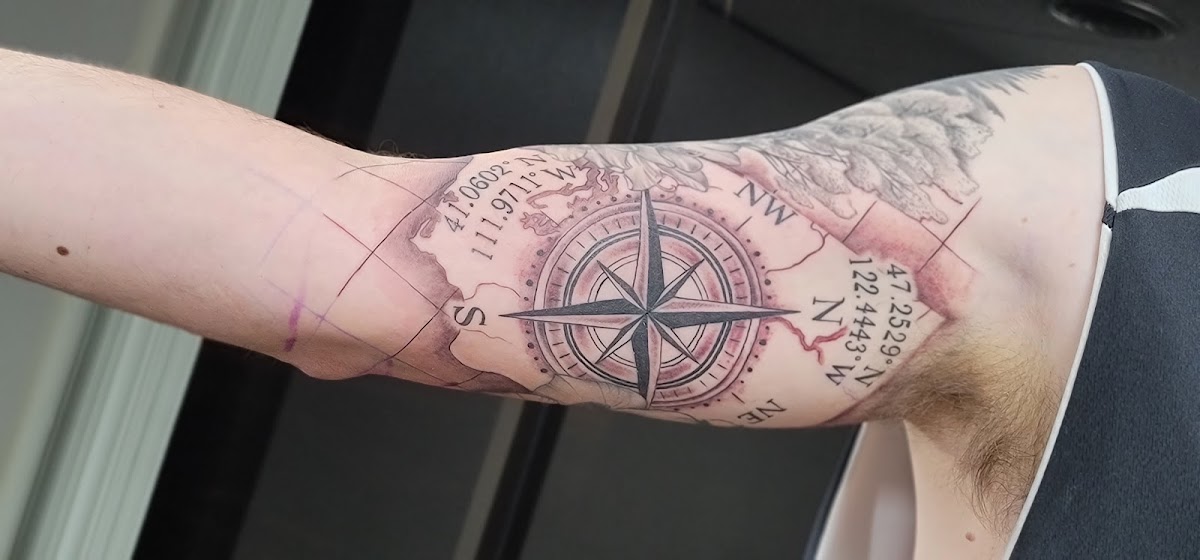 Black and grey compass and antique map tattoo with coordinates